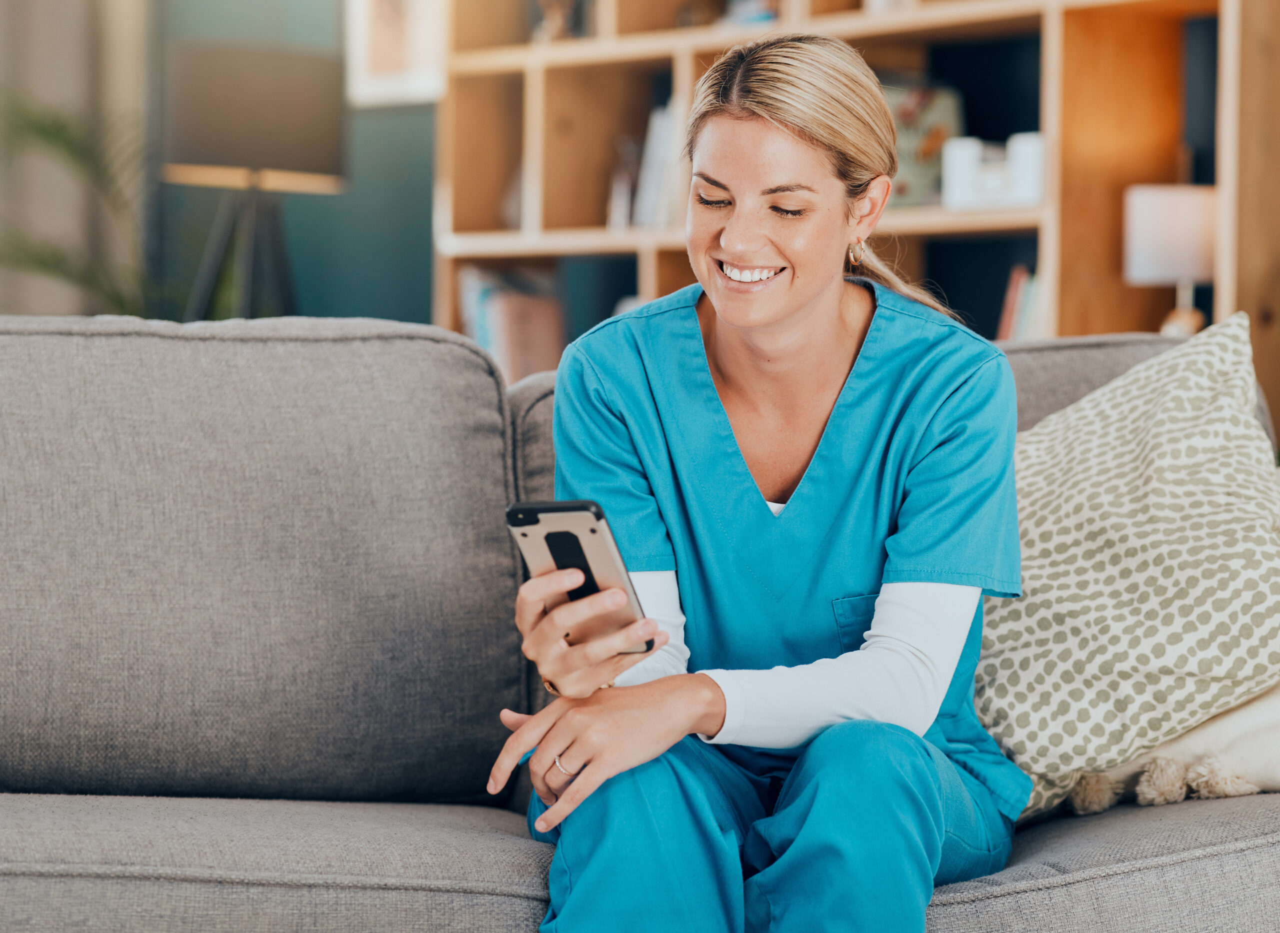 Triage nurse providing after-hours home-based care while reviewing patient information on a phone.